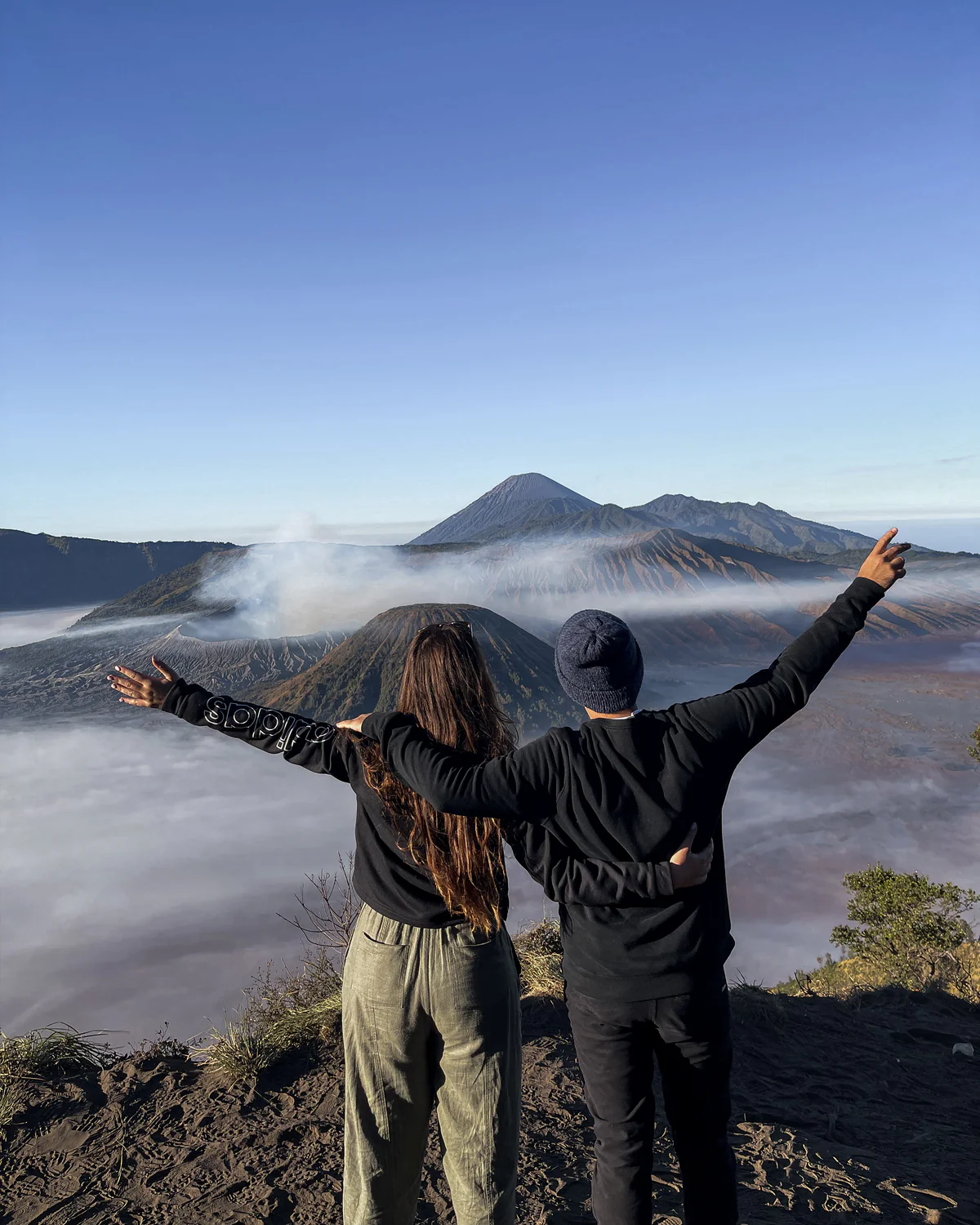 Two adventurers on a mountain overlook looking out over a misty valley